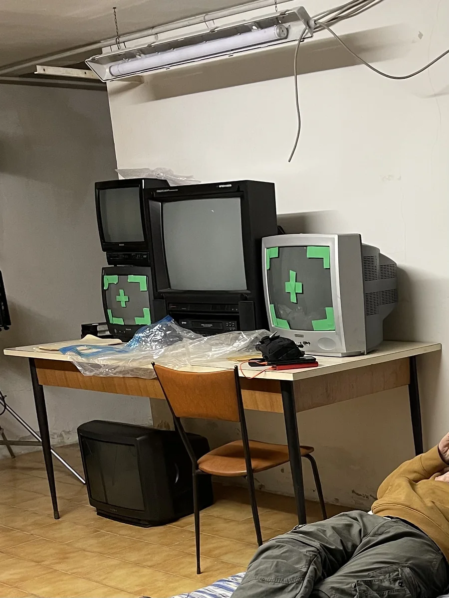 Il set nella cantina: i televisori coperti di nastro adesivo, il neon appeso, i cavi